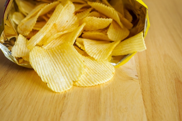 Sacchetto aperto di patatine fritte sulla tavola di legno