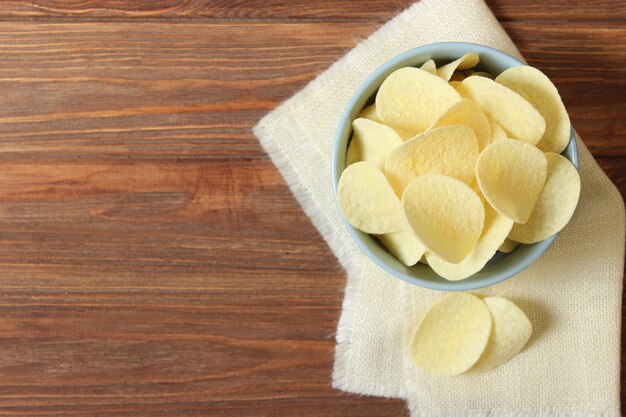 Potato chips in a plate on a colored background top view