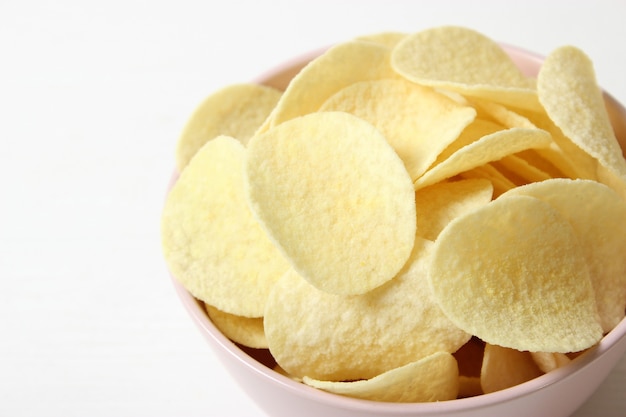 Potato chips in a plate on a colored background top view