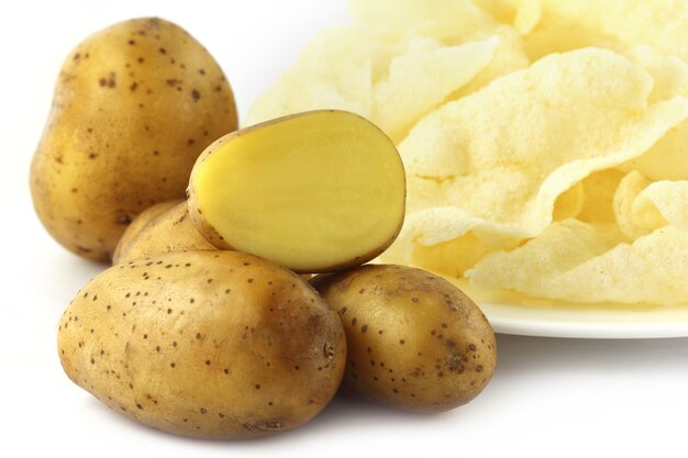 Potato chips with fresh potatoes over white background