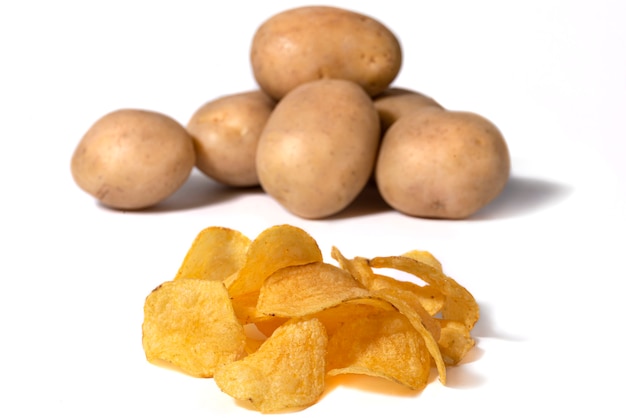 Potato chips with salt and potato tubers in the background on a white background