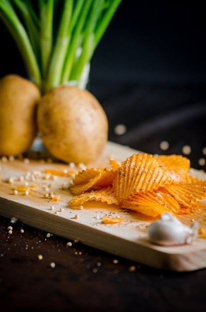 Potato Chips with vegetable and garlic on a wooden chopping board