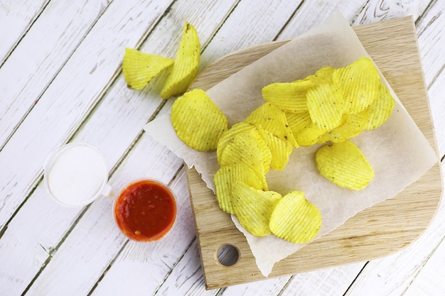 Potato chips on a wooden tray on a white table