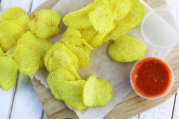 Potato chips on a wooden tray on a white table