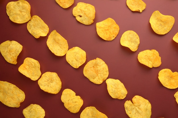 Potato crisps pattern, top view on red background