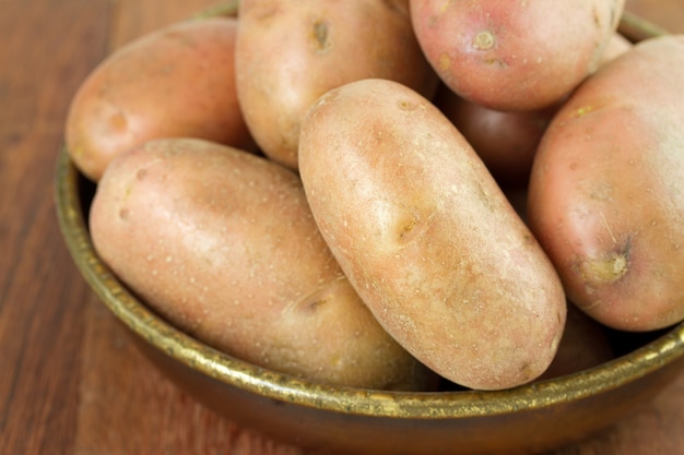 Potato in dish on brown background