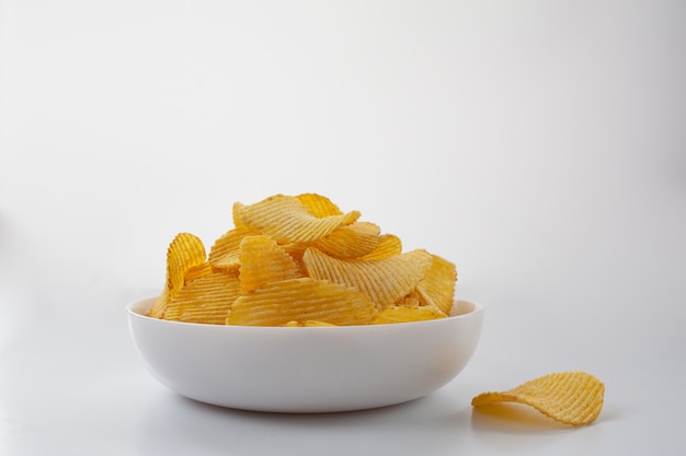 Foto patatine fritte scanalate in un piatto bianco su sfondo bianco.