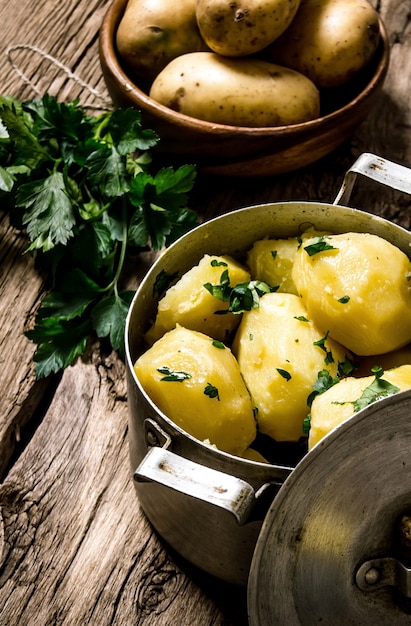 Potato food . Boiled potatoes with herbs on wooden table .