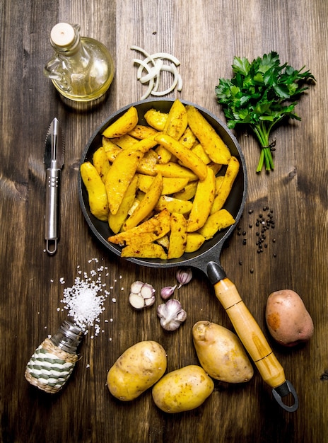 감자 음식. 향신료, 소금, 기름, 허브와 마늘 나무 테이블에 구운 감자의 개념. 평면도