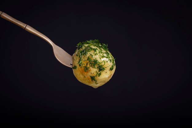 Potato on a fork with black background