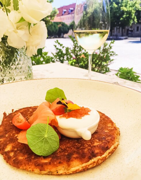 Potato fritter pancake with red caviar salmon and sour cream in luxury restaurant outdoors in summer