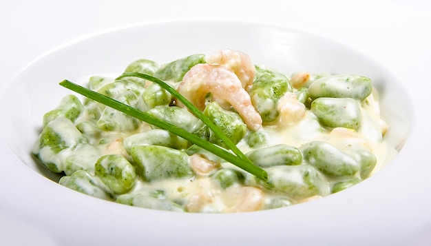 Potato gnocchi with spinach and shrimp on white background