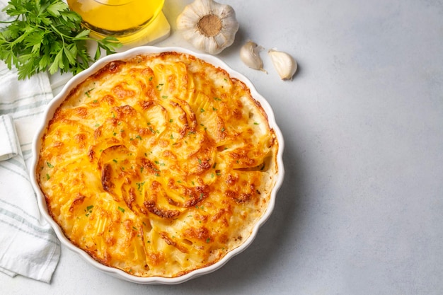 Potato gratin - graten (baked potatoes with cream and cheese) with rosemary and forks (Turkish name; Kremali patates)