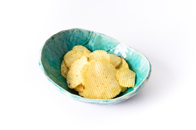 Potato grooved chips in a homemade ceramic plate turquoise on a white background