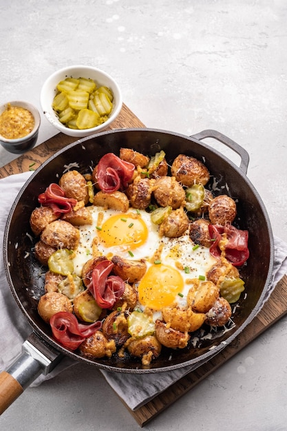 Potato hash with fried eggs and meat pastrami for breakfast branch