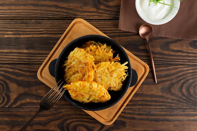 Картофельные блинчики draniki Latkes или Levivot в чугунной сковородке с кислым сливком Ханука Пасхальная еда