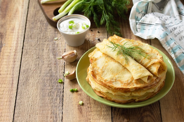 Potato pancakes not sweet served with garlic cream sauce on rustic wooden table Copy space