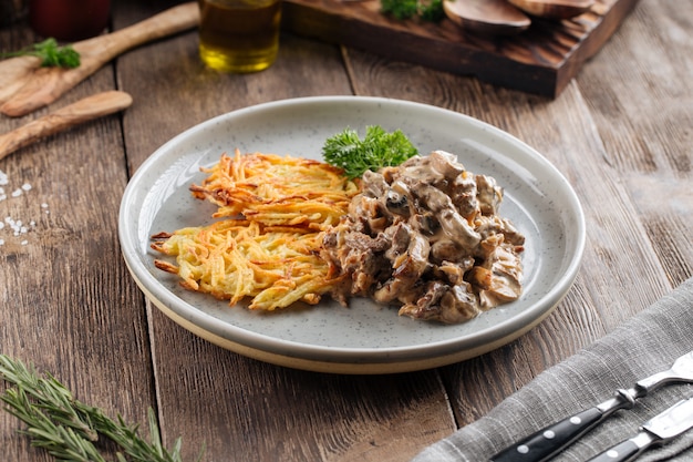 Potato pancakes with beef stroganoff on grey plate