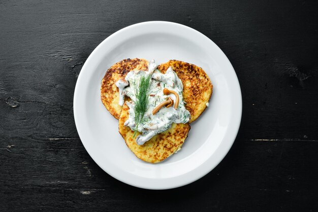 Potato pancakes with mushroom sauce. On a wooden background. Top view. Free space for your text.