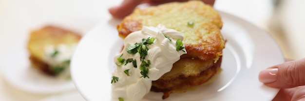 접시에 사워 크림과 허브를 곁들인 감자 팬케이크