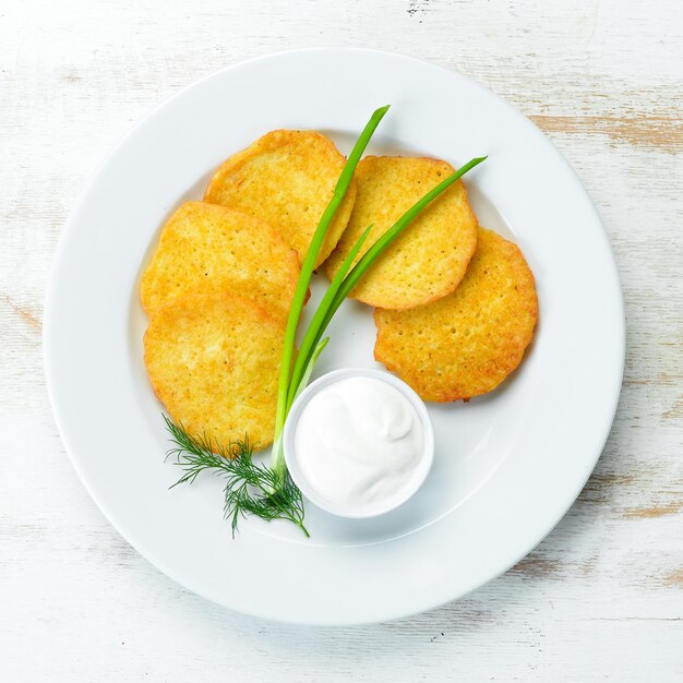 Foto frittelle di patate con panna acida e cipolle. vista dall'alto. spazio libero per il tuo testo.