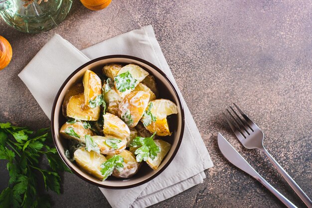 Foto insalata di patate in una buccia con prezzemolo e maionese in una ciotola sulla vista del tavolo