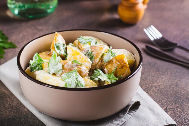 Photo potato salad in a peel with parsley and mayonnaise in a bowl on the table