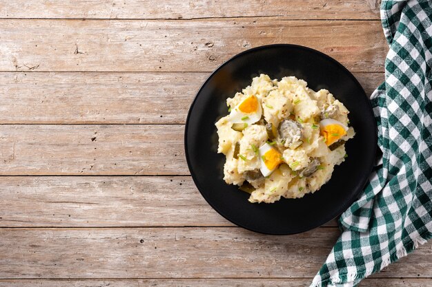 Potato salad with gherkins, egg and mustard on wooden table