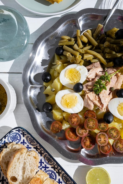 Картофельный салат с тунцом, вареным яйцом, стручковой фасолью, помидорами черри и оливками с соусом винегрет