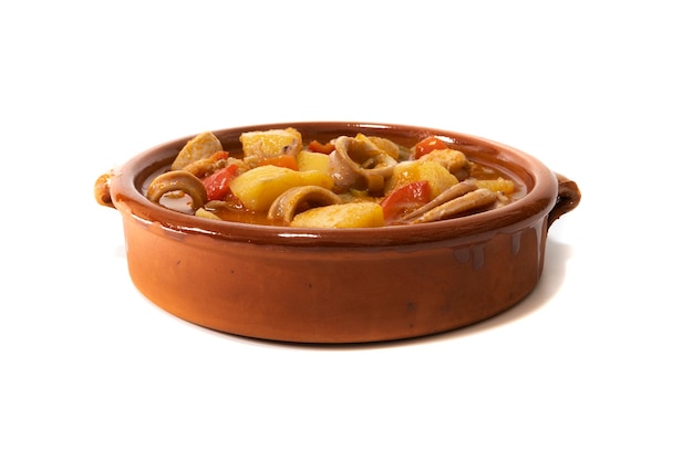 A potato stew with calamari served in a clay bowl isolated on a white background Spanish food