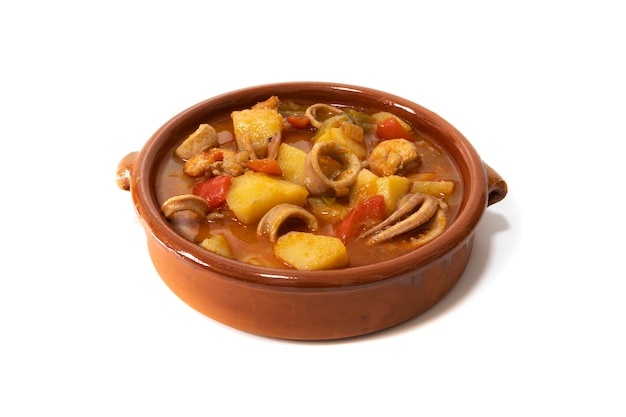 A potato stew with calamari served in a clay bowl isolated on a white background Spanish food