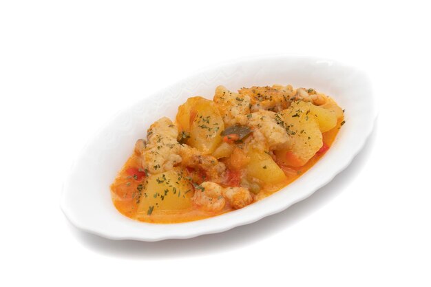 Potato stew with cod shrimp and parsley on top served on a white plate White background