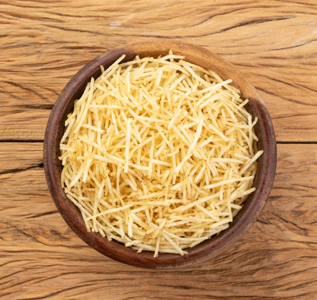 Potato straw or shoestring potato in a bowl over wooden table.