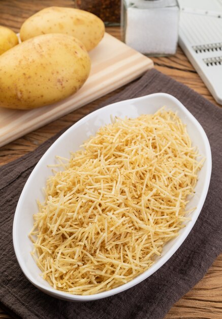 Potato straw or shoestring potato in a white plate with raw potatoes