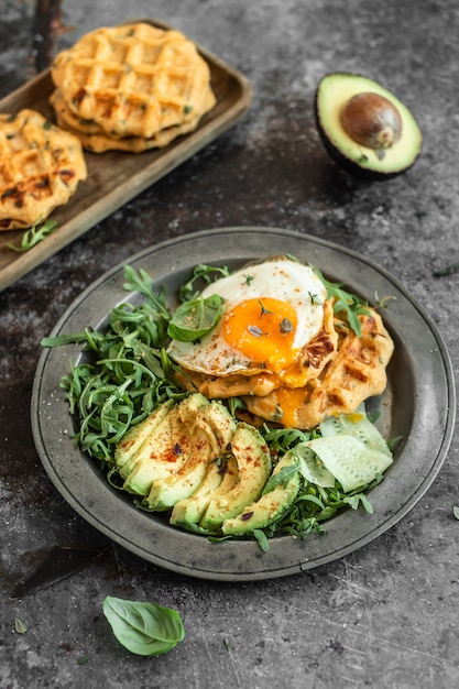 Potato waffle with a fried egg, avocado, and fresh arugula