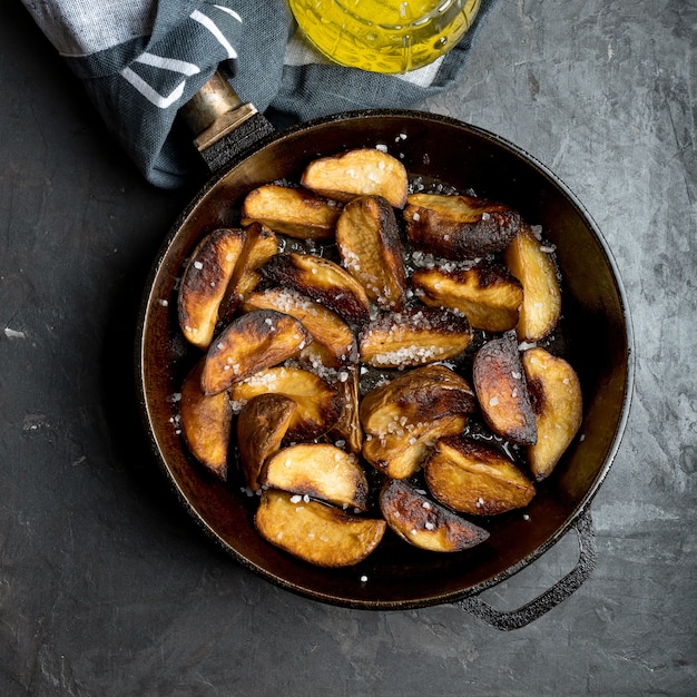 Potato wedges, iron pan, knife and oil