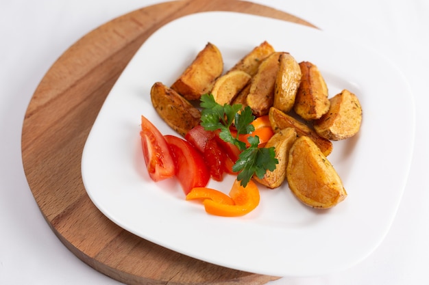 Potato wedges with tomatoes and peppers on a white background