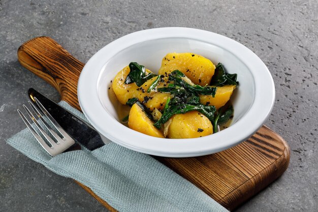 Photo potato with spinach in white plate over grey concrete background