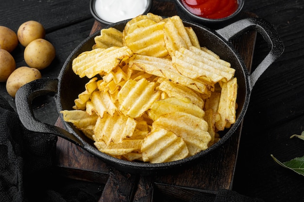 Potatoe chips on black wooden background