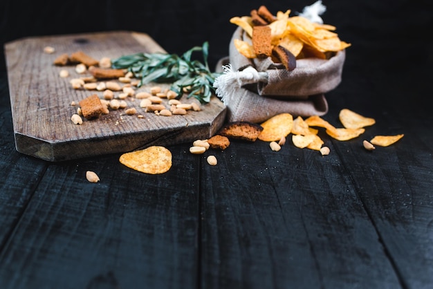 Potatoe chips, peanuts and crackers on black