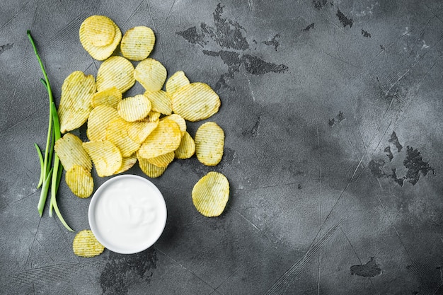 Potatoe chips set, with dipping sauces, on gray stone table, top view flat lay