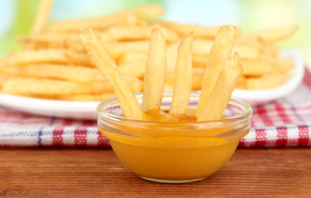 Potatoes fries on the plate with sauce on wooden background closeup