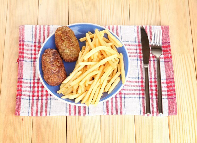 Foto patate fritte con hamburger sul piatto sullo sfondo in legno