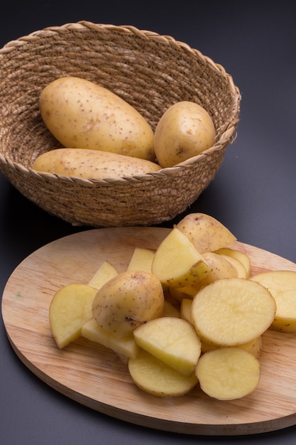 Potatoes and potato sliced In the basket on a black background