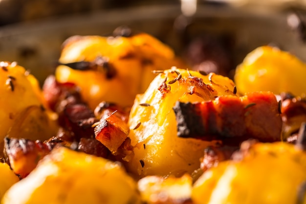 Potatoes. Roasted potatoes with bacon onion and sausages on old oak table.