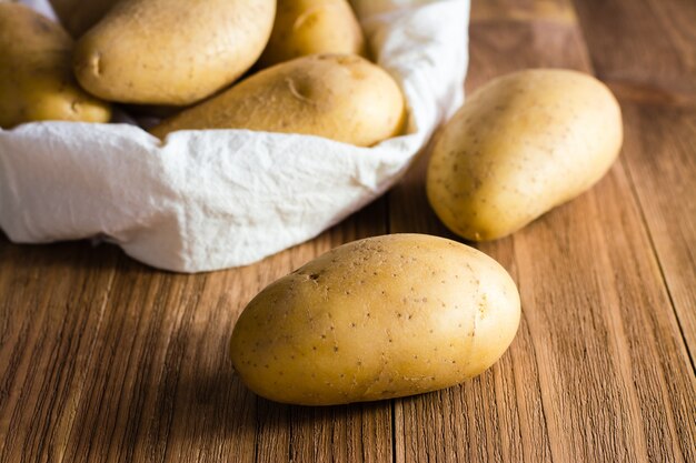 The potatoes on the of the sack of potatoes on a wood table