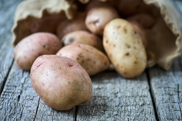 Potatoes which just fell out of the burlap sack lying on the wood boards