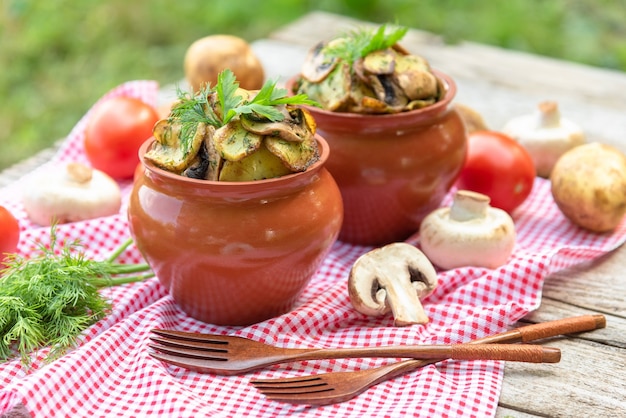 Patate con funghi in una pentola di terracotta