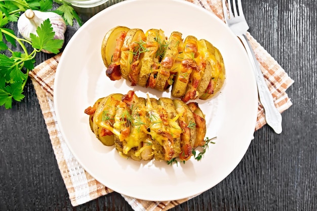 Potatoes with smoked bacon in plate on dark board top