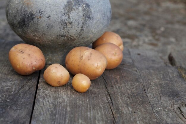 potatoes on a wooden board near retro rural pot for cooking